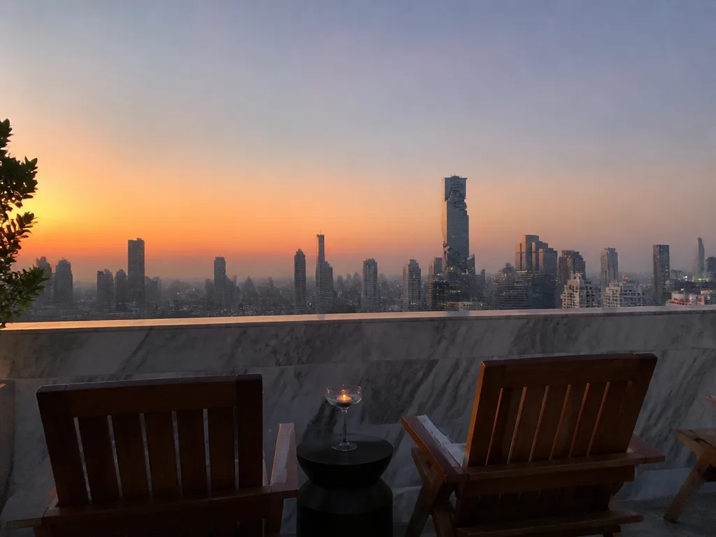Empty rooftop bar terrace at golden hour overlooking Bangkok skyline