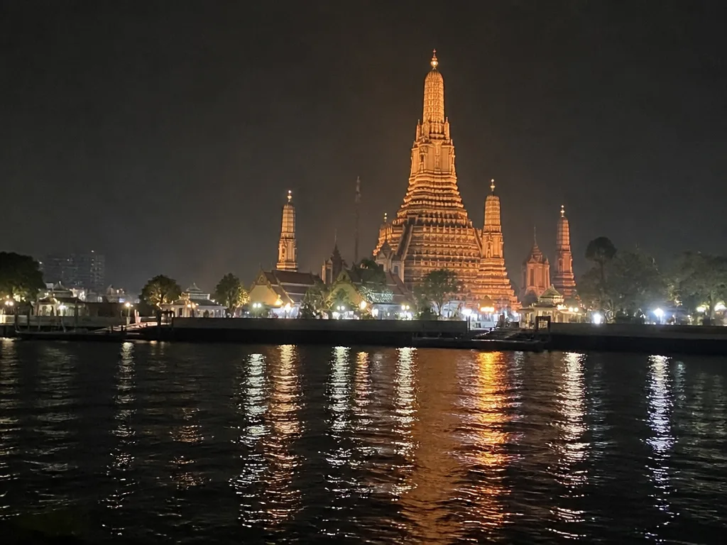 Wat Arun temple lit at night seen from across the Chao Phraya river