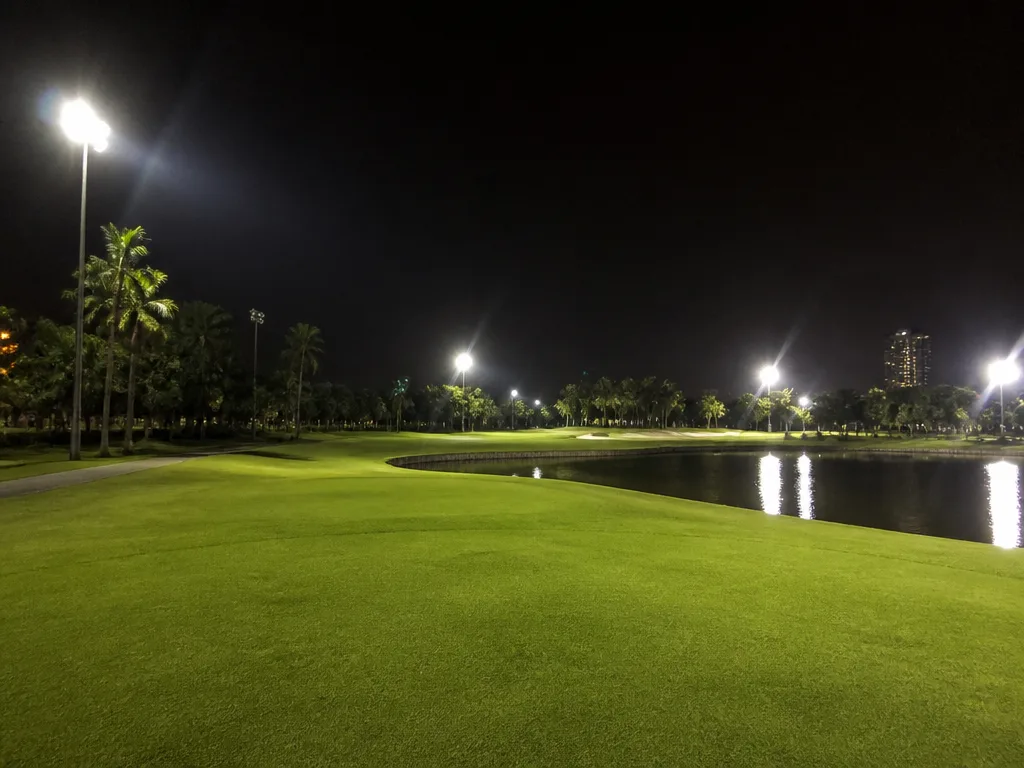 Floodlit night golf fairway under stadium lights in Bangkok