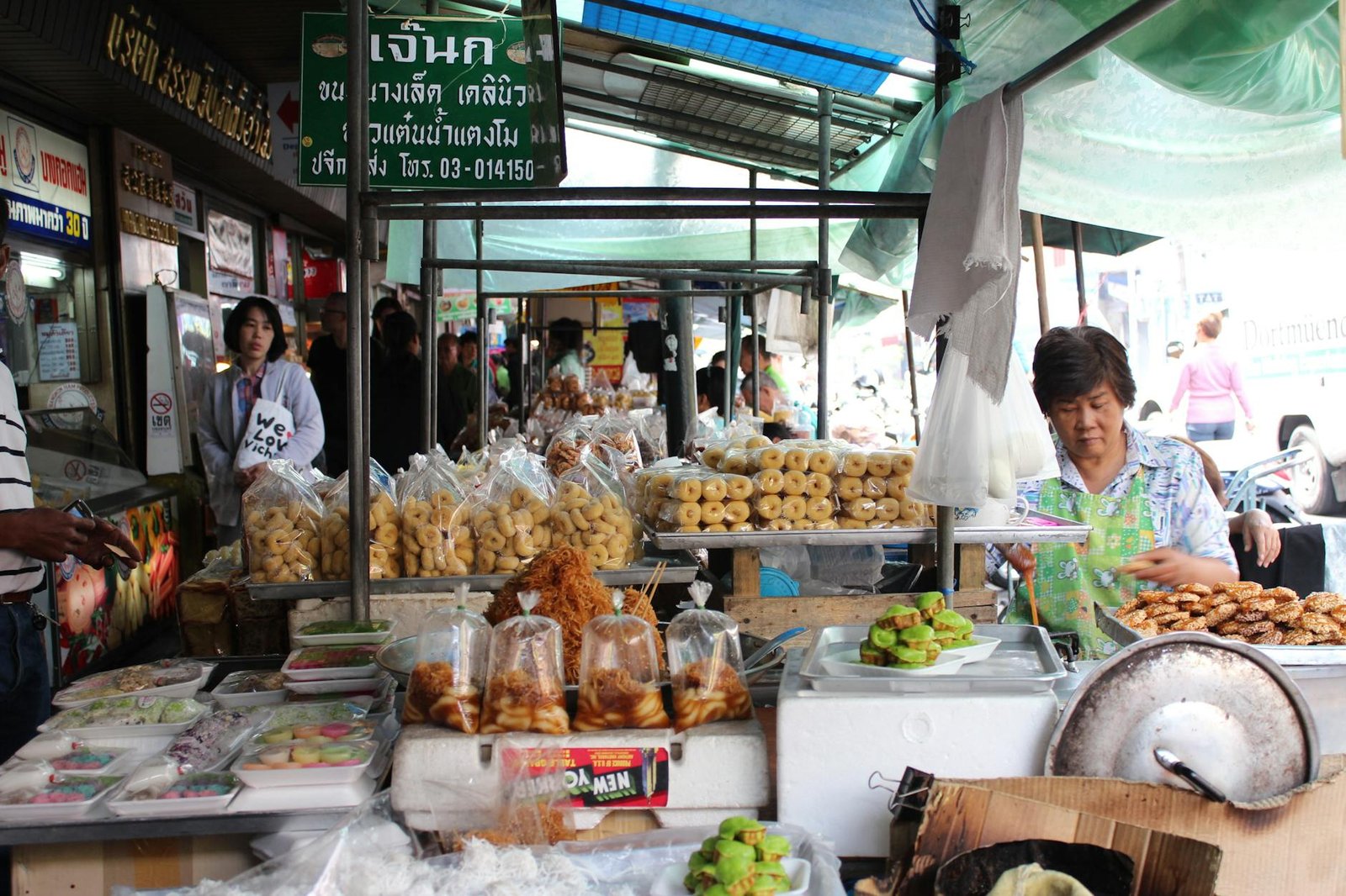 Street food vendor handling cash in a Bangkok market with fresh produce on display