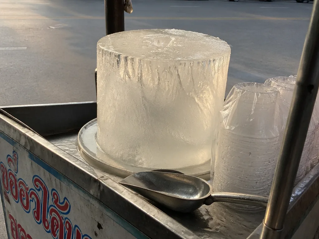 Cylindrical commercial ice block on Bangkok street vendor cart