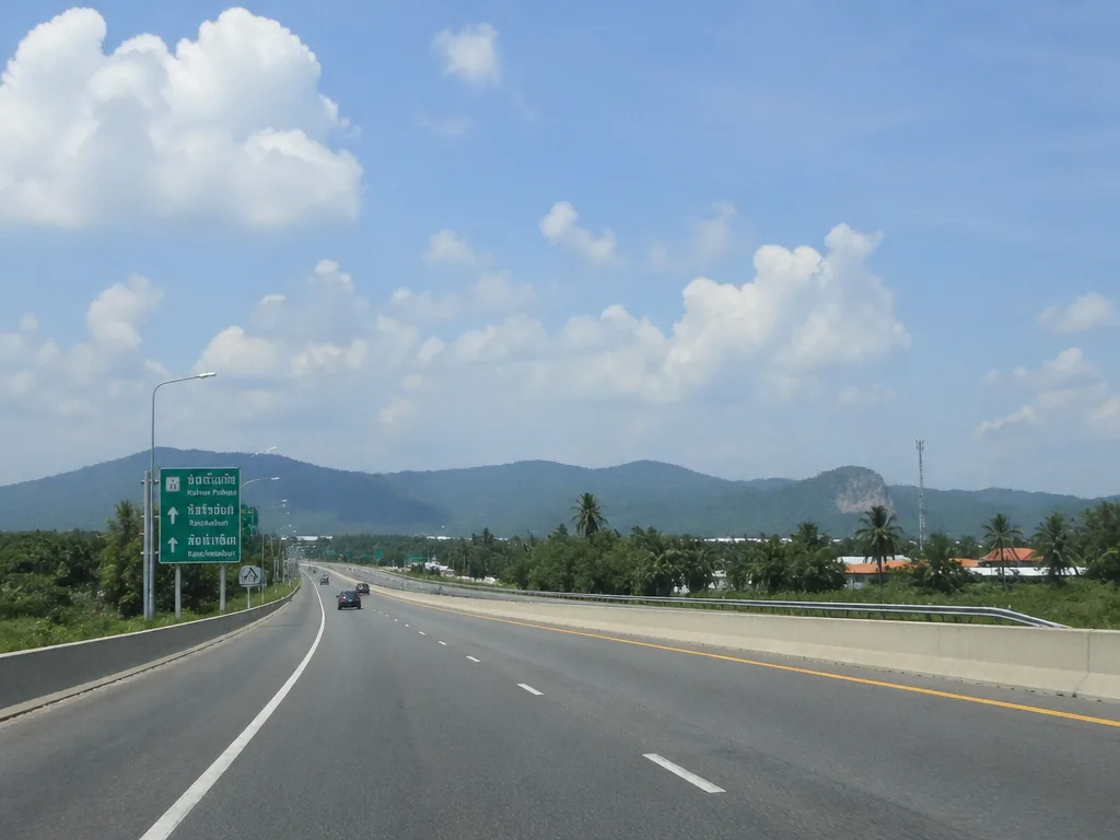 Highway leaving Bangkok with green mountains on horizon