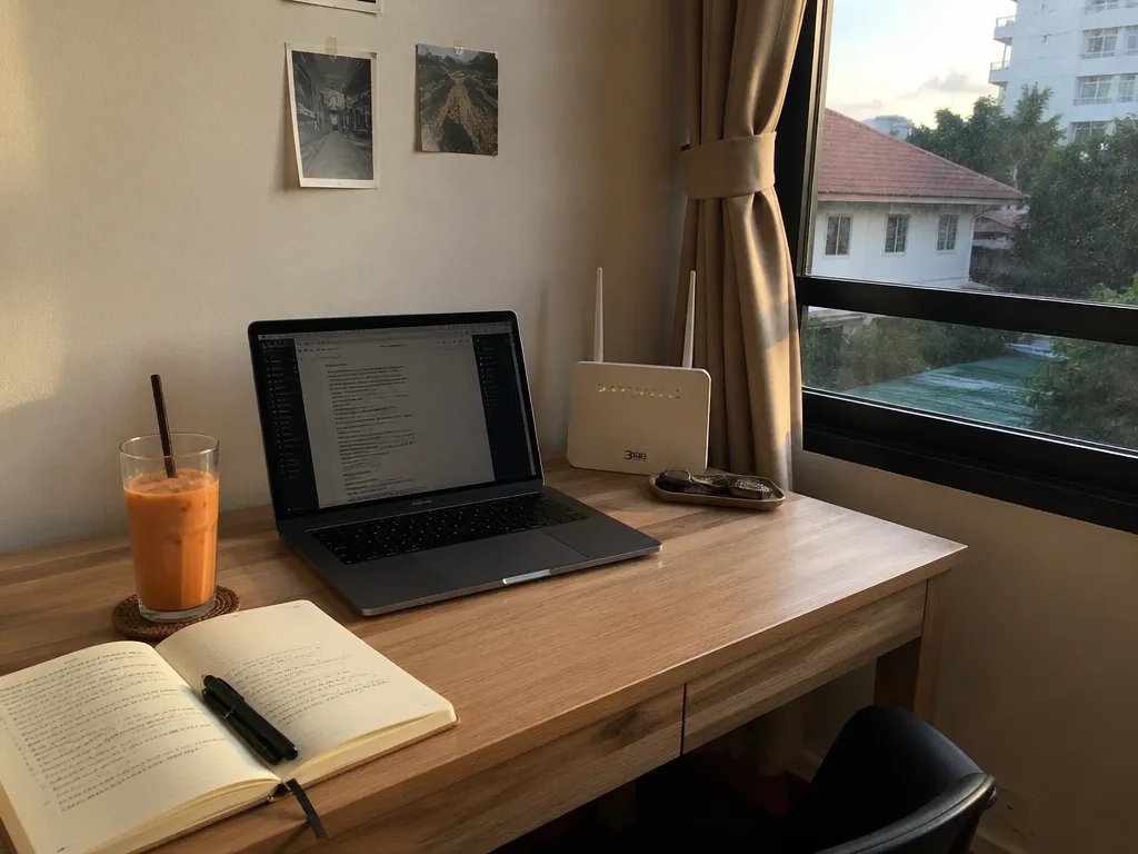 Small Chiang Mai studio apartment work desk with laptop and fiber router