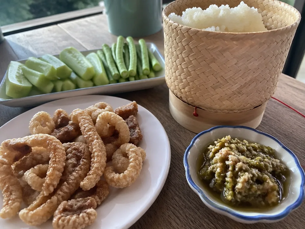 Nam prik noom green chili dip and pork rinds with a basket of sticky rice