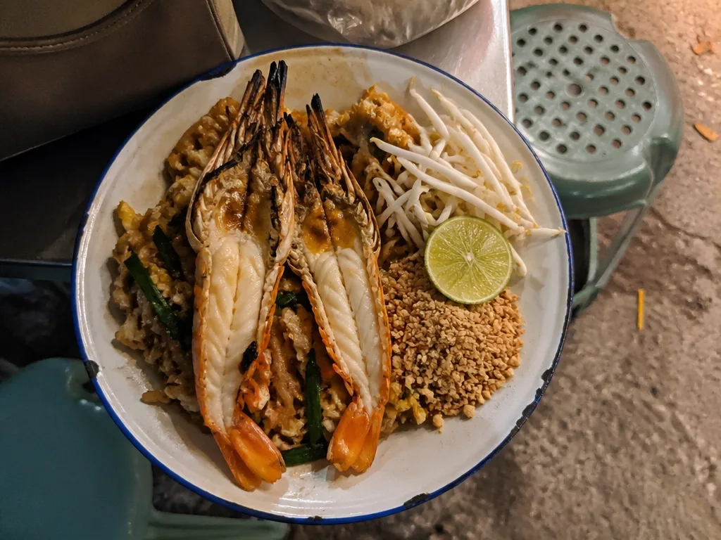 Plate of pad thai with prawns and lime at a Chaweng noodle cart