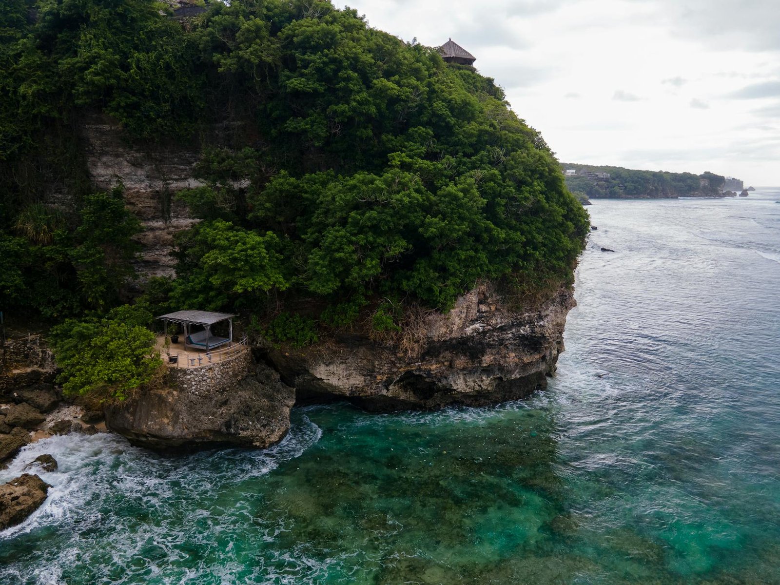 朝焼けのターコイズブルーの海を見下ろす崖のウェルネス・リゾート・パビリオン
