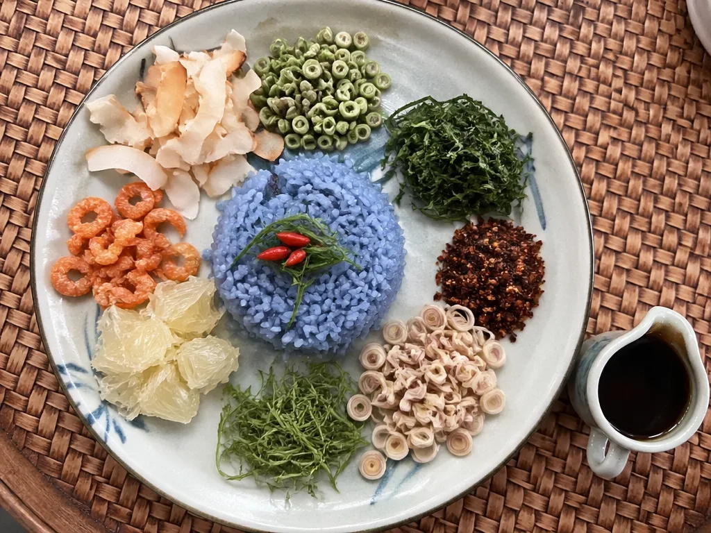 Plate of Khao Yam southern mixed rice salad with blue butterfly pea rice and colorful toppings