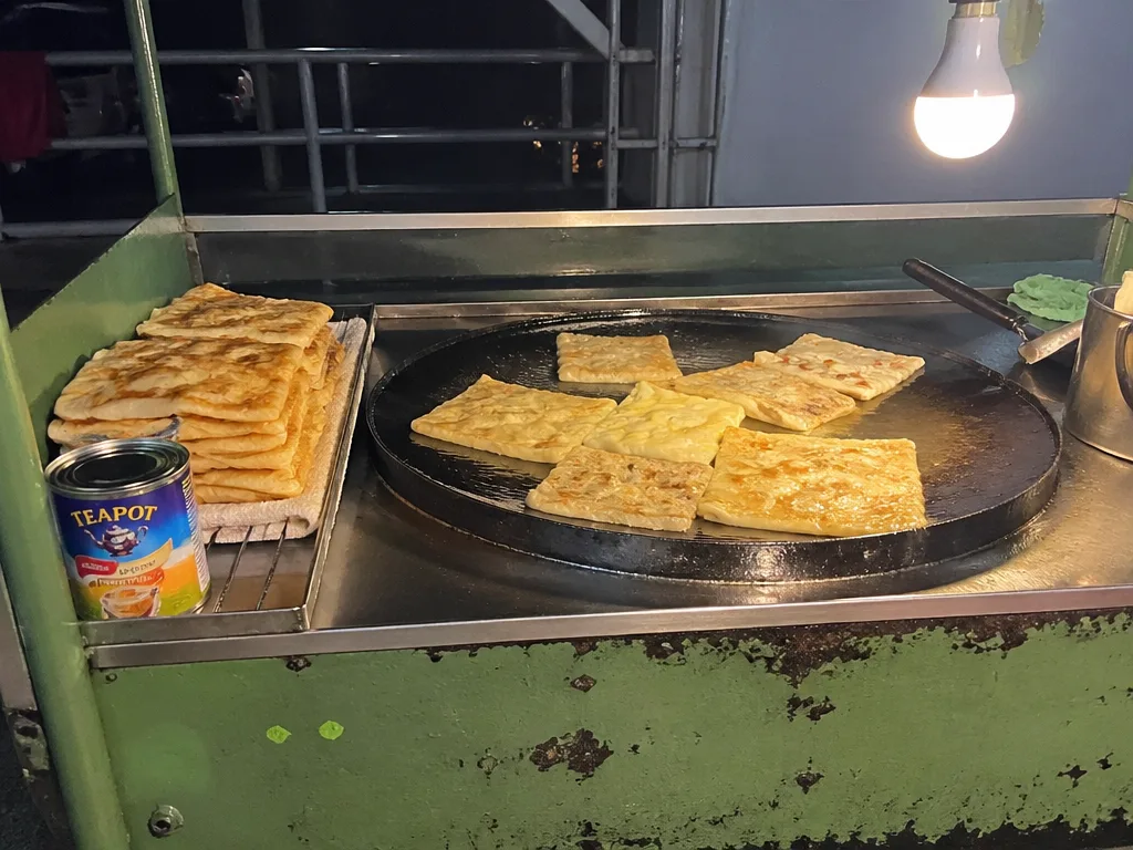 Roti vendor cart on a Krabi Town street corner cooking fresh flatbread on a flat-top griddle