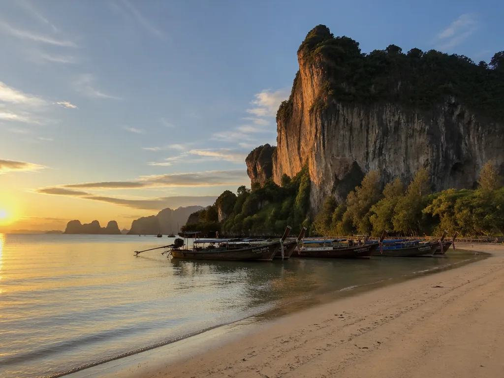 Railay West beach sunset golden cliffs longtail boats