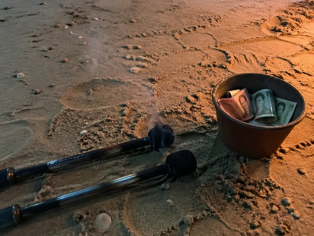 Burnt-out fire poi sticks resting on the sand after a beach show in Ao Nang