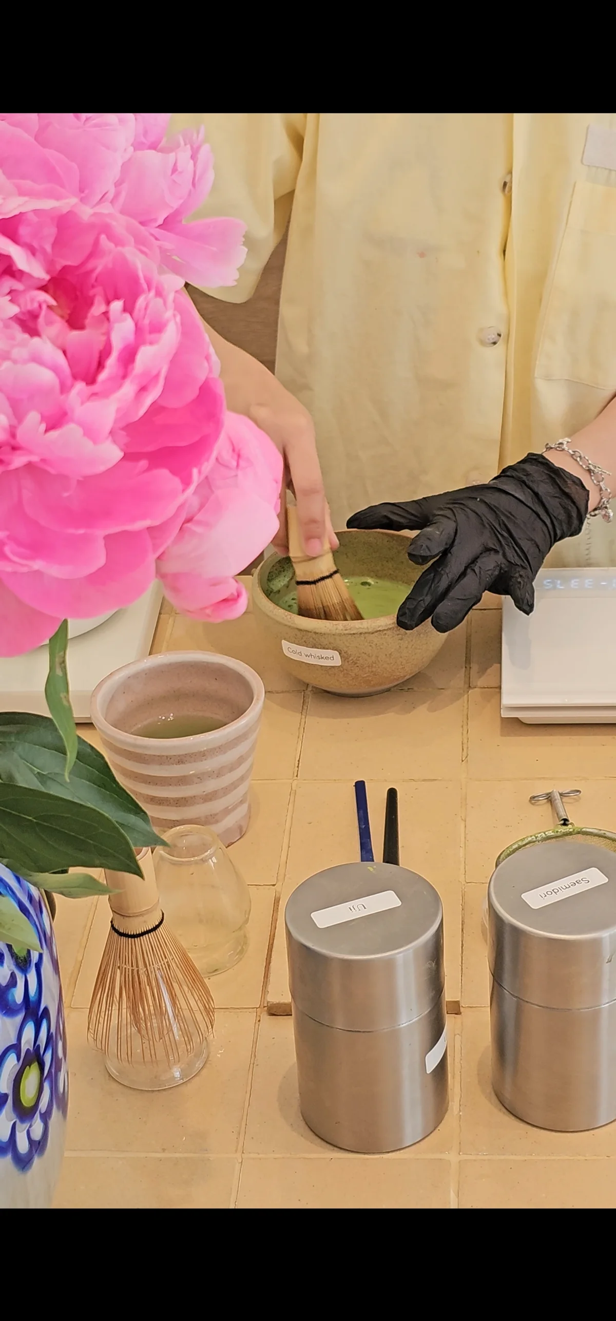 Cold whisked ceremonial matcha bowl beside a pink peony