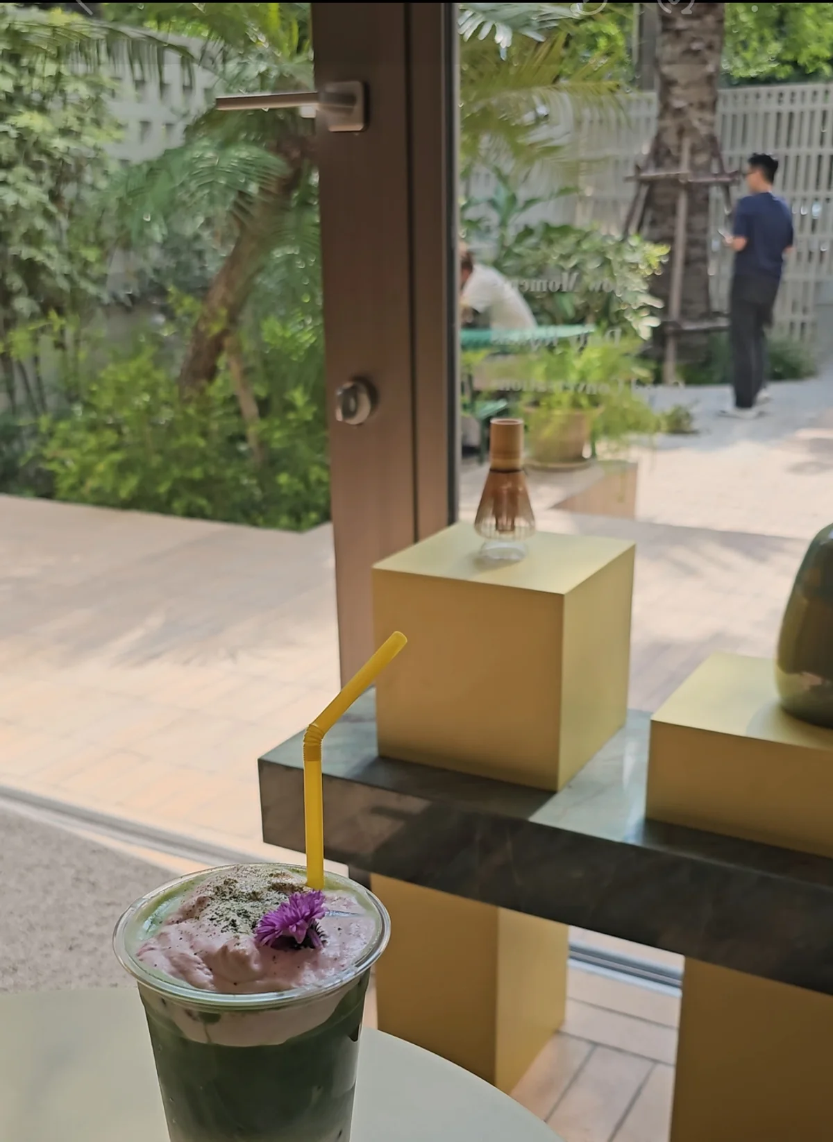 Iced matcha strawberry drink topped with an edible purple flower