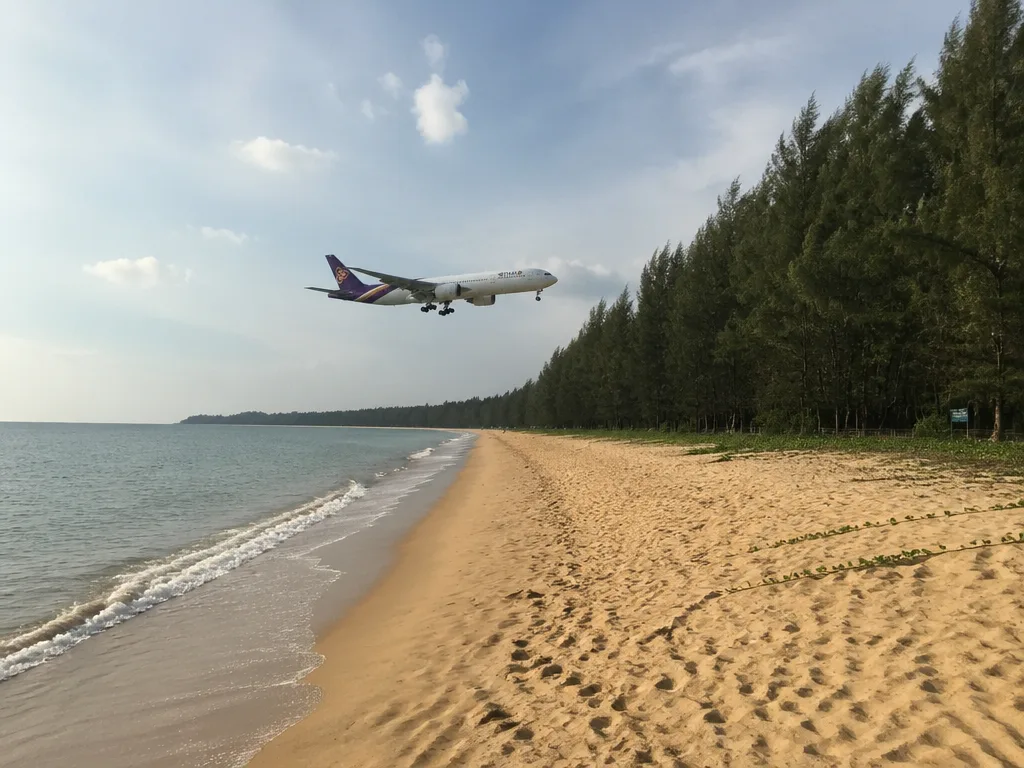 Empty Mai Khao Beach with airplane low over the sand