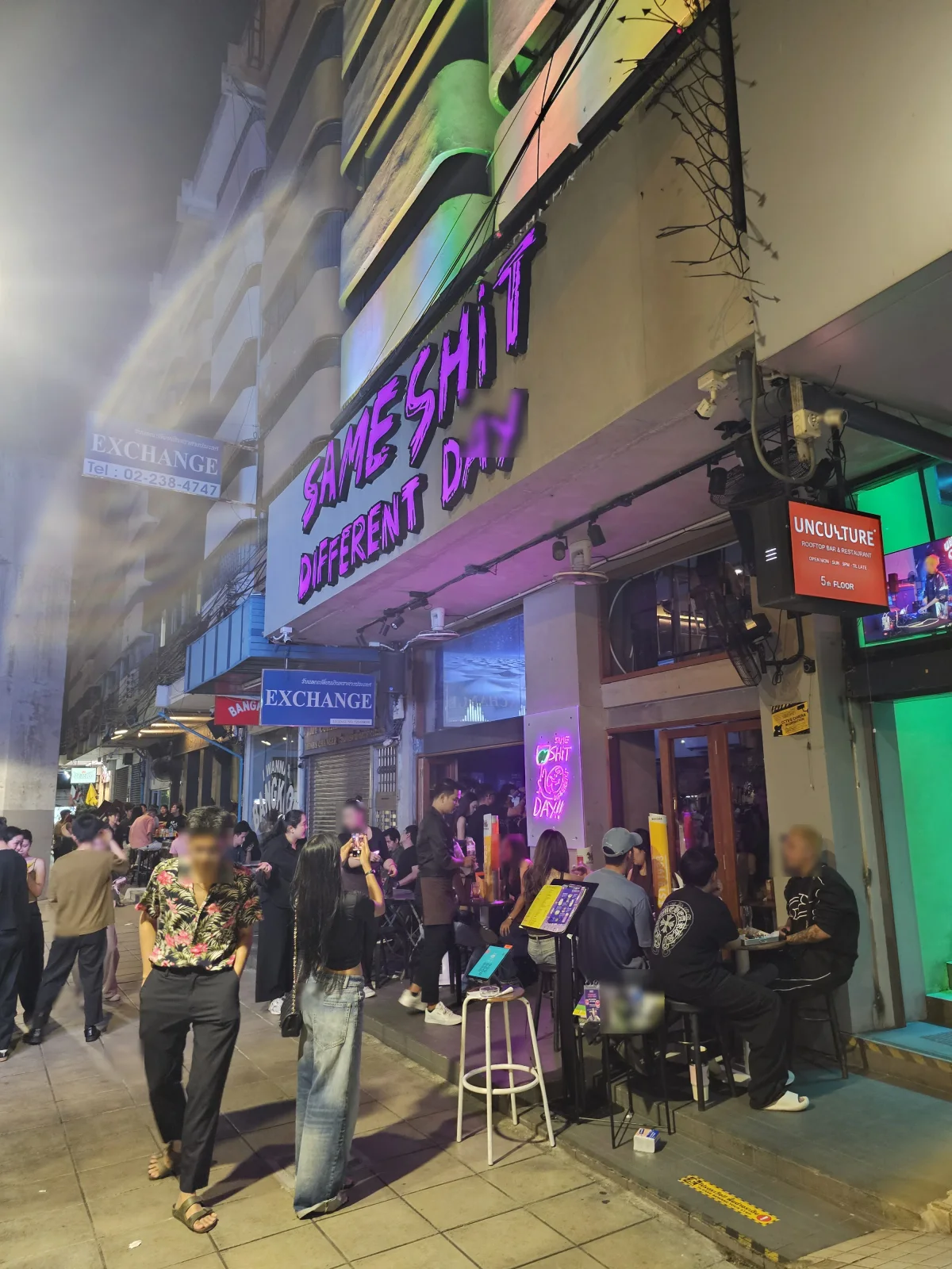 SSDD Sathorn exterior with lit neon sign and street crowd