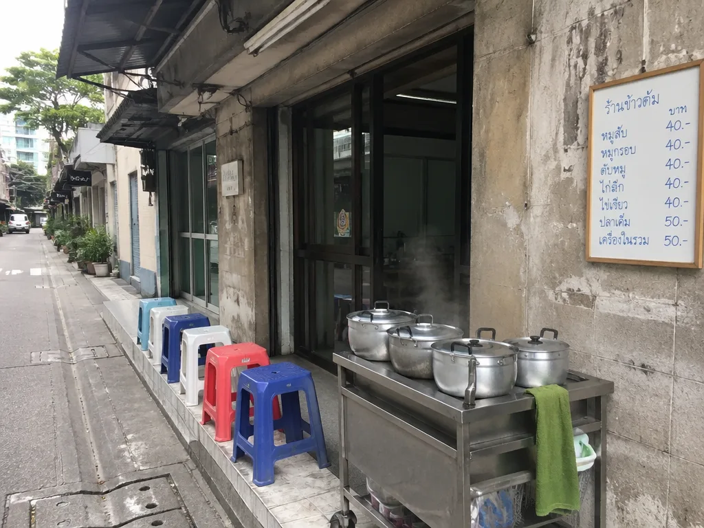 Plastic stools and steaming pots lining a busy Bangkok soi at lunchtime