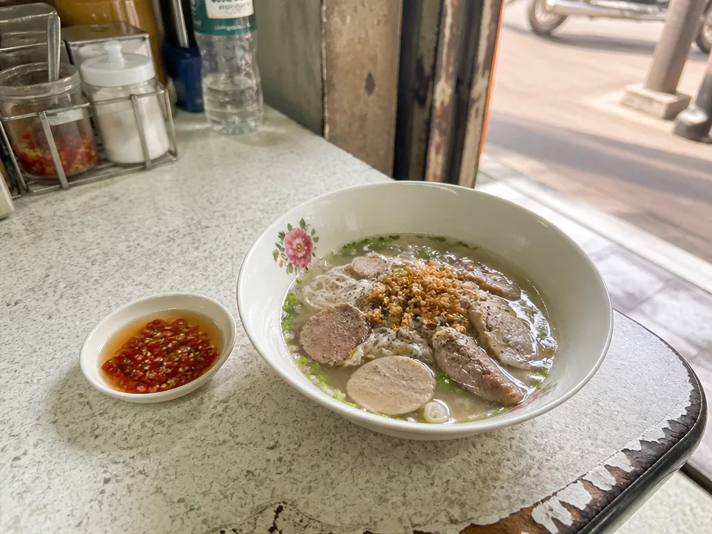Bowl of clear pork noodle soup with crispy garlic at a Phrom Phong shop
