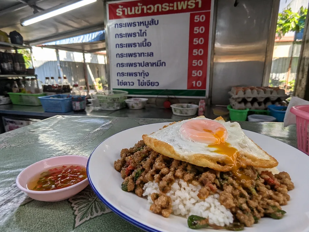 Lunch market stall serving made-to-order pad kra pao with fried egg
