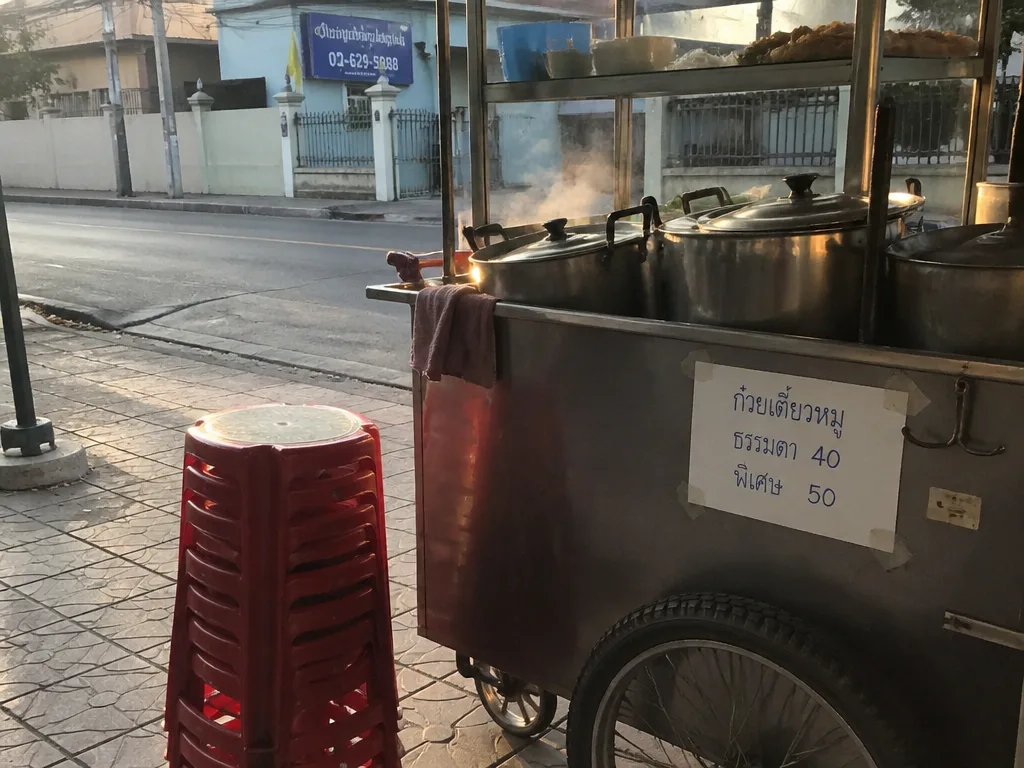 Bangkok street food cart with stainless steel pots and stools