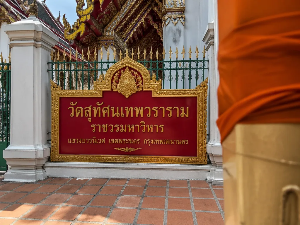 Thai temple entrance with gold lettering on red signboard